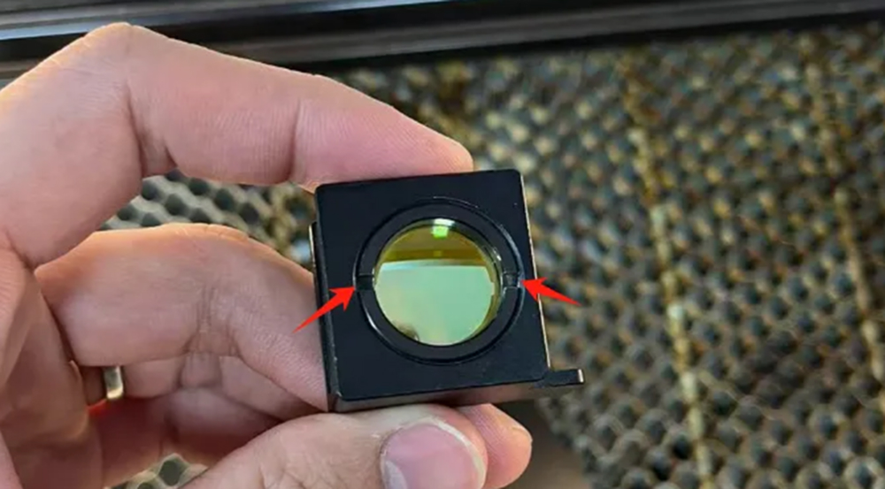 Unscrewing the retaining ring to remove a laser focusing lens